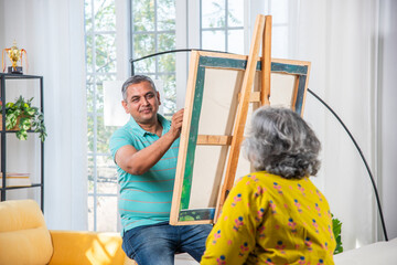 Senior Indian male artist painting picture in studio - obrazy, fototapety, plakaty