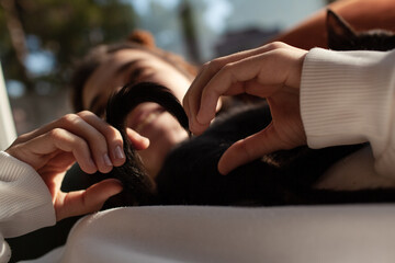 A young beautiful girl is lounging on the coach with a black kitten at home. The cat relaxation with the hostess