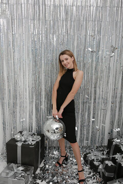 foil rain curtain. beautiful girl in a black dress New Year's photo .mirror disco ball and silver confetti. Festive splash background with shining sparkles. Silver glass disco ball. Party atmosphere 