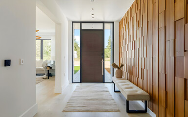 Hall with bench against wooden 3d paneling wall. Minimalist interior design of modern home entryway with door.