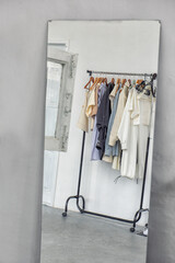 Hanger with clothes in a white room with old walls and an old wooden window