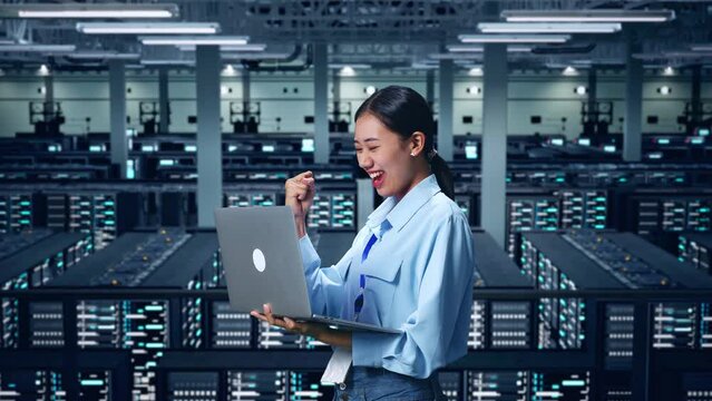 Side View Of Happy Asian Business Woman Celebrating Using Laptop Computer In Data Center