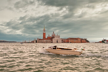 Taxi and other boat traveling on the lagoon and the island of San Giorgio Maggiore in the background in the Venice Lagoon in Veneto, Italy