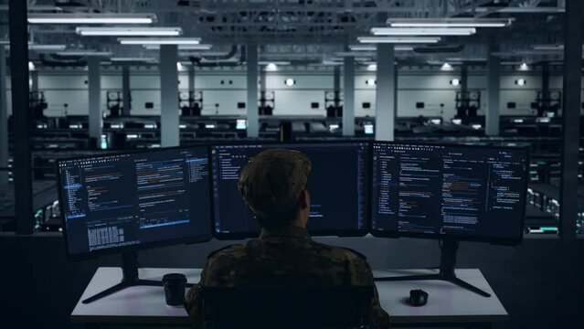 Back View Of Tired Asian Military Yawning While Write Code With Multiple Computer Screens In Data Center