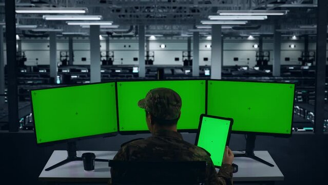 Back View Of Asian Military Working With Tablet And Multiple Computer Monitor With Mock Up Green Screen In Data Center