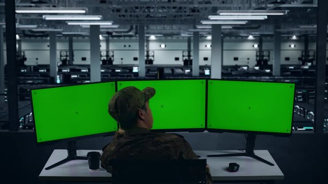 Back View Of Bored Asian Military Working With Mock Up Multiple Computer Monitor In Data Center