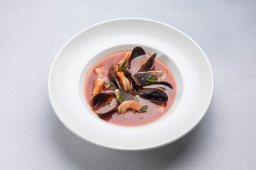 Seafood soup with salmon and mussels in a white plate