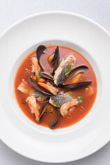 Seafood soup with salmon and mussels in a white plate