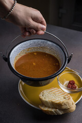 Soup with meat and vegetables in a pot on a dark background