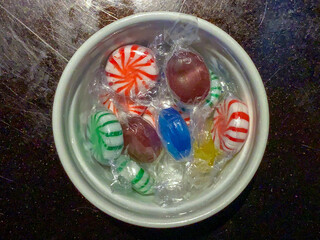 Hard candies wrapped in cellophane in a white ramekin