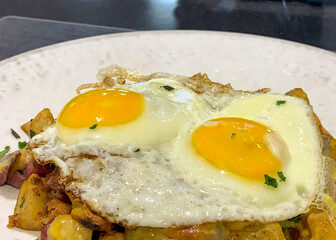 Sunny side up fried eggs on top of a potato hash served for breakfast