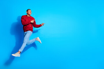 Full body portrait of sporty crazy guy jump look direct fingers empty space isolated on blue color background