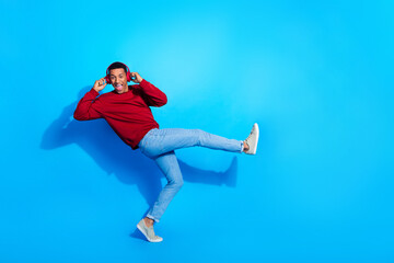 Full length profile portrait of cheerful nice person arms touch headphones rejoice dance empty space isolated on blue color background