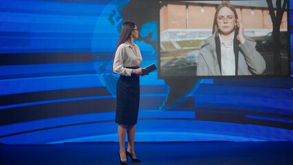 Female presenter in the studio. Woman news host presenting daily events, talking on air with reporter outside, breaking news background at the back.