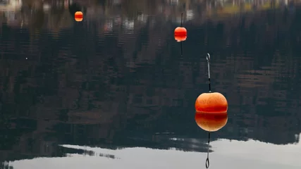 Foto op Canvas Czerwone, pomarańczowe, jaskrawe boje unoszą sie na tafli górskiego jeziora. © Tomasz