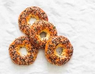 Homemade crispy bagels with seeds on a light background, top view