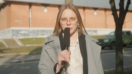 Female presenter reporting on air outside. Woman news host journalist talking with studio, wearing...