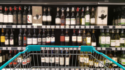 Green shopping cart with blurred image of alcohol store in background. (Selective focused at shopping cart).