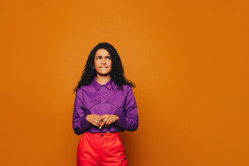 Happy woman with curly hair on vibrant orange background.