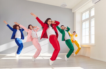 Team of five male and female dancers rehearsing in modern white dance studio. Group of happy,...