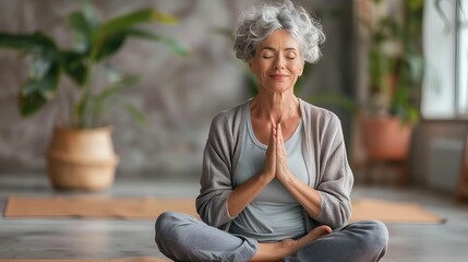 Smiling mature woman meditating, sitting in a yoga studio, inner peace cultivation