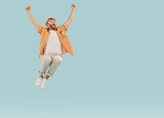 Joyful man celebrating success with victorious shout and jump on pastel light blue background....