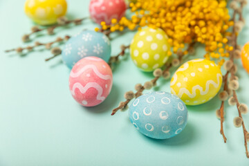 Easter eggs with mimosa flowers on a bright background. Easter celebration concept. Colorful easter handmade decorated Easter eggs. Place for text. Copy space.