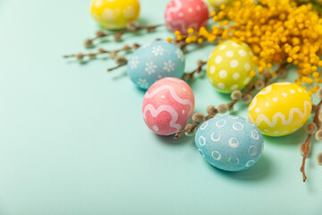 Easter eggs with mimosa flowers on a bright background. Easter celebration concept. Colorful easter handmade decorated Easter eggs. Place for text. Copy space.