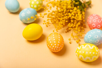 Easter eggs with mimosa flowers on a bright background. Easter celebration concept. Colorful easter handmade decorated Easter eggs. Place for text. Copy space.