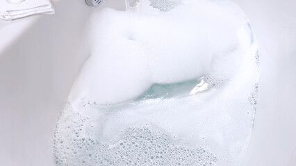 Modern White Bathtub Filled with Running Water from a Brushed Nickel Faucet