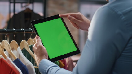 Store assistant swiping mockup tab computer at fashion shop closeup. Man working