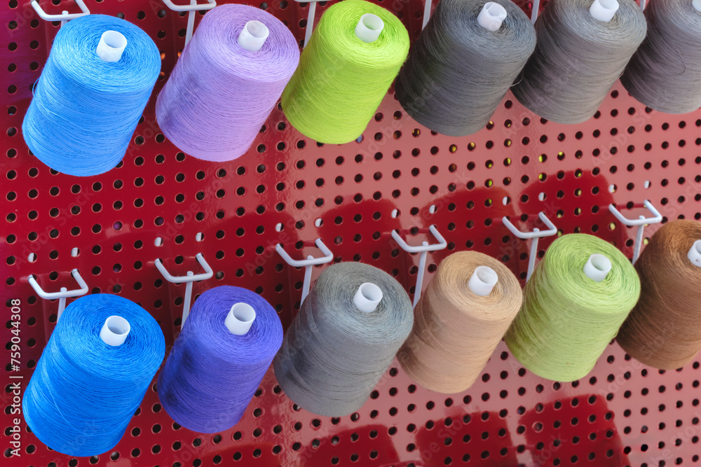 Aufkleber a row of colorful spools of thread are displayed in a store. the spools are arranged in a rainbow pa