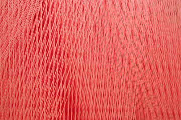 A red threads and fibers with a pattern of lines and dots as a texture background. The fabric is...