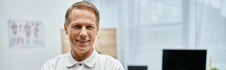 jolly attractive doctor posing and smiling at camera while in hospital ward, rehabilitation, banner
