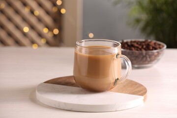 Delicious coffee with milk in cup on white wooden table