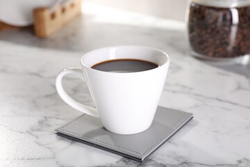 Delicious coffee in cup on white marble table, closeup