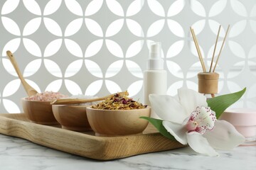 Beautiful composition with different spa products and orchid on white marble table