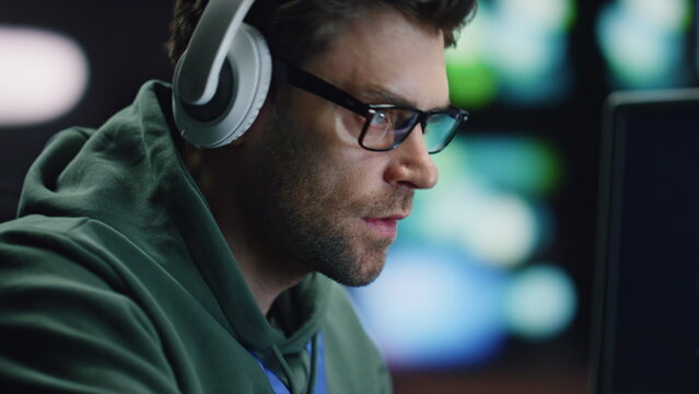 Closeup coder hands typing keyboard in night data center. Man enjoying music