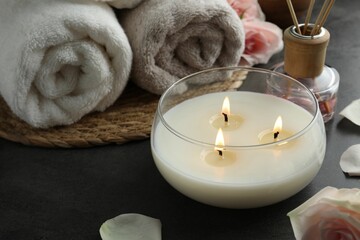 Fototapeta na wymiar Spa composition with burning candle and towels on grey table, closeup