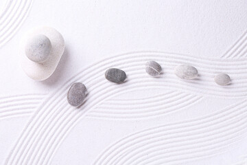 Zen garden stones on white sand with pattern, flat lay