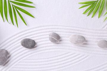 Zen garden stones and green leaves on white sand with pattern, flat lay