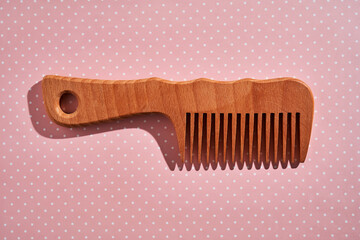 Wooden comb on a pink polka dot background.