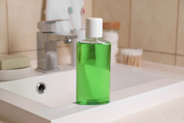 Fresh mouthwash in bottle on sink in bathroom, closeup