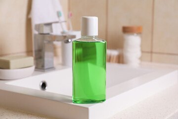 Fresh mouthwash in bottle on sink in bathroom, closeup