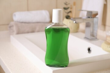Fresh mouthwash in bottle on sink in bathroom, closeup