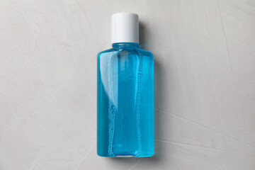 Fresh mouthwash in bottle on grey textured background, top view