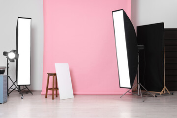 Pink photo background, stool and professional lighting equipment in studio