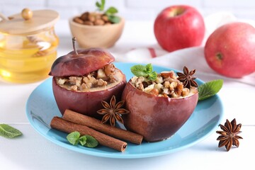 Tasty baked apples with nuts, honey, spices and mint on white wooden table