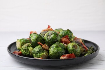 Delicious roasted Brussels sprouts, bacon and rosemary on white textured table, closeup