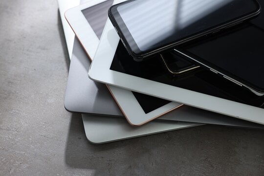 Many different modern gadgets on grey table, closeup